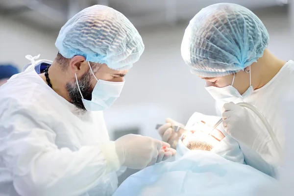 Surgeon and nurse during a dental operation.Anesthetized patient in the operating room.Installation of dental implants or tooth extraction in the clinic. General anesthesia during orthodontic surgery.