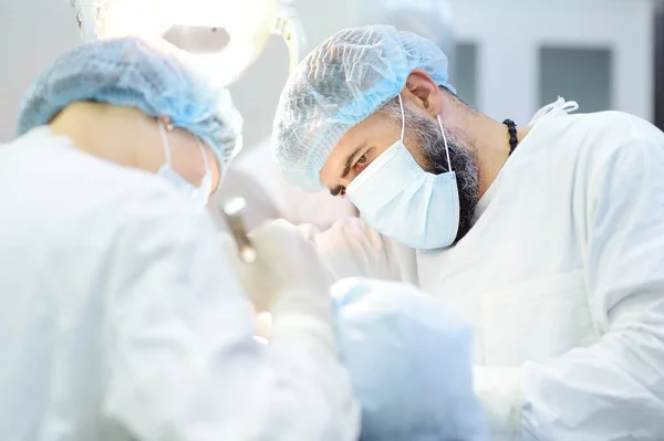 Surgeon and nurse during a dental operation.Anesthetized patient in the operating room.Installation of dental implants or tooth extraction in the clinic. General anesthesia during orthodontic surgery.