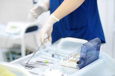 Cerrah ya da asistan klinikte ameliyat sırasında steril enstrüman kullanıyor. Çelik tıbbi aletler kullanılmaya hazır. Modern ekipman, aletler ve ameliyat için teknoloji. Sağlık ve İlaç.