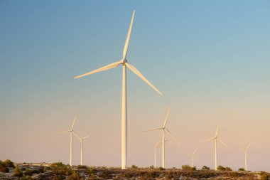 Yenilenebilir enerji üretimi için rüzgar santrali grubu. Günbatımında yel değirmenleri. Jenerasyon elektriği için yüksek rüzgar türbinleri. Yeşil enerji kavramı.