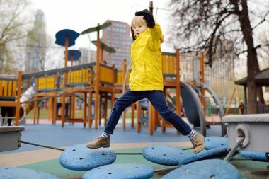 Sevimli anaokulu çocuğu dışarıda oyun parkında eğleniyor. Çocuklar için ilkbahar sonbaharı aktif spor eğlencesi. Çocuklu aile aktivitesi. Çocuklar için eğlence parkı için modern ekipman.