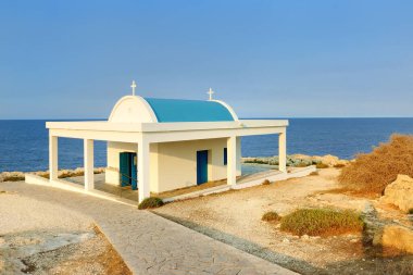 Kıbrıs Rum Kesimi 'nin Cape Cavo Greco kentindeki Agioi Anargyroi Şapeli' nin günbatımı manzarası. Ayia Napa yakınlarındaki güzel mavi ve beyaz kilise Kıbrıs adasındaki Akdeniz kıyısındaki bir uçurumda
