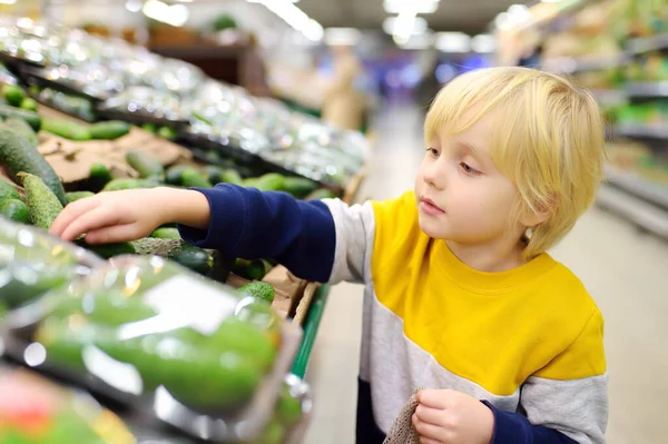 可爱的小男孩在食品店或超市里挑选新鲜的有机黄瓜 有孩子家庭的健康蔬菜 带孩子购物 — 图库照片