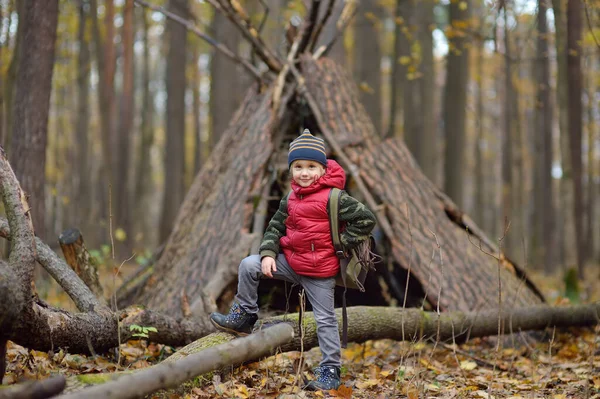 小男孩在秋天的森林里徒步旅行时侦察 孩子的后面是小茅屋 儿童探险 探险及远足旅游的概念 — 图库照片