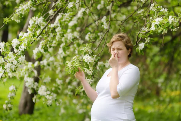 在春天的公园里散步时 怀孕的年轻女子用餐巾打喷嚏和擦鼻涕 流感季节 冷鼻炎 过敏的人 生病的人 准妈妈 — 图库照片