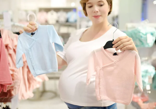 Young Pregnant Woman Choosing Pink Girl Blue Boy Clothes Store — стоковое фото