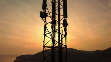 Gün batımının inanılmaz yakın çekim görüntüsü baz istasyonunun silueti. Kablosuz bağlantı. Arka planda dağlar ve deniz olan hücre kulesinin muhteşem manzarası. 5G ağı. & Site