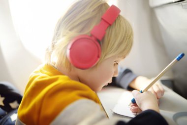 Uçakla seyahat eden sevimli bir çocuk. Çocuk müzik dinlemek için oyuncu kullanıyor ya da uçuş sırasında ses kaydedip resim çiziyor. Uçakta çocuklu bir aile eğlencesi.