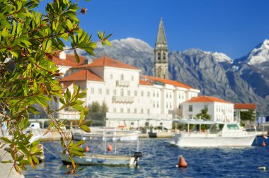 Karadağ 'ın antik Perast kentinin resimli manzarası. Adriyatik denizinin arka planında kırmızı çatıları ve görkemli dağları olan eski bir ortaçağ kasabası. Tekneli ünlü Kotor Körfezi.