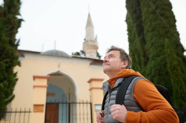 Olgun bir turist, Bosna-Hersek 'in eski Trebinje kentinde gezintiye çıkıyor. Sırt çantalı kişi, Trebinye 'nin tarihi merkezindeki Osman Paşa Camii cephesini inceliyor