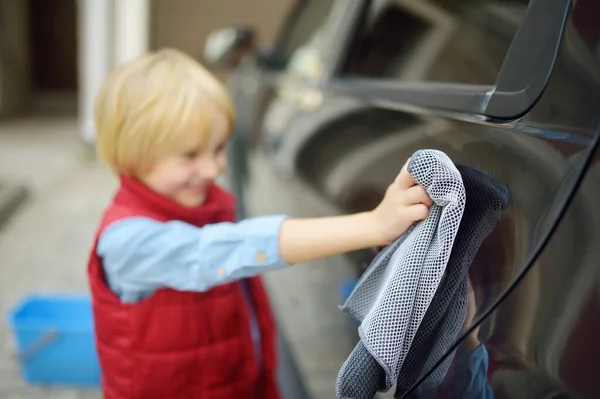 小男孩在车库附近洗黑色的车 孩子们玩得很开心还帮他的父母家庭抚养 教孩子工作 把重点放在餐巾上 — 图库照片