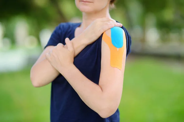 肩にキネシオテープをかけた女性 運動機能障害やその他の身体障害による痛みや障害を緩和する方法が報告されています 腎臓学 理学療法 リハビリテーション — ストック写真