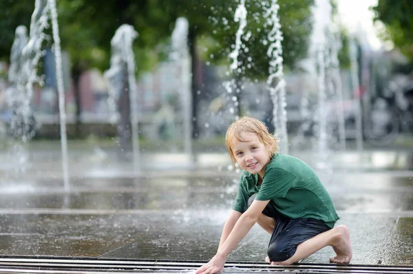 夏天阳光灿烂的时候 小男孩在雪地喷泉里的水柱之间的正方形里玩耍 大城市里孩子们积极的夏季休闲活动 — 图库照片