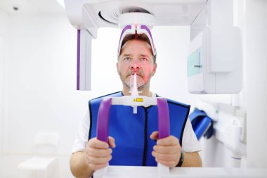 Diş hekimliği kliniğinde panoramik radyografi sırasında hasta olan bir adam. Hastane, klinik ve tıp merkezi için modern diş ekipmanları ve teknolojileri.