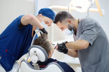 Surgeon and nurse during a dental operation. Anesthetized patient in the operating room.Installation of dental implants or tooth extraction in the clinic. General anesthesia during orthodontic surgery