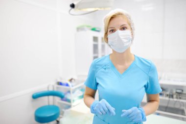 Tıbbi maske ve koruyucu eldiven takan kadın cerrahın portresi. Doktor ameliyathanede ameliyata hazırlanıyor. İlaç ve sağlık hizmetleri.