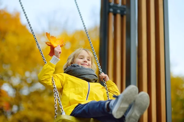 秋の日に公園の遊び場でスイングを楽しんでいる小さな男の子 幸せな子供はスイングをお楽しみください 市内の子供のためのアクティブな屋外レジャー — ストック写真