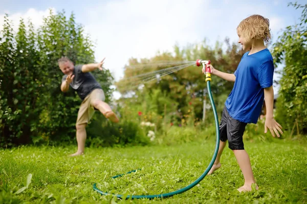 Funny Little Boy His Father Playing Garden Hose Sunny Backyard — Zdjęcie stockowe