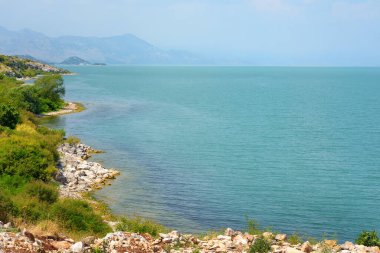 Stunning view of the shore of wonderful Skadar lake on the background of mountains. Giant Skadar Lake is a famous bird nature reserve in Balkans located in Albania and Montenegro. Travel and tourism.