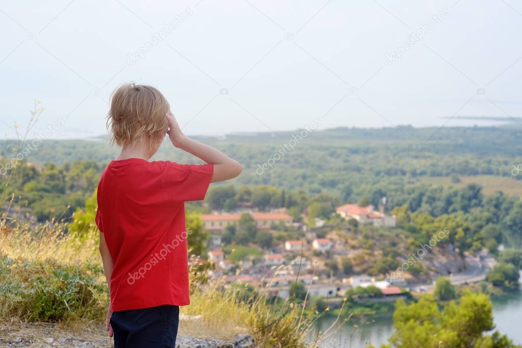 Little child tourist visiting famous fortress Rozafa near Shkodra city. Boy admiring view of valey river Buna, Skadar Lake and mountains. Travel and tourism in Balkan