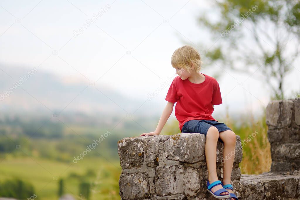 Little child tourist visits famous fortress Rozafa near Shkodra city. Boy watching ancient stone walls and towers of bastion. Interest in history of children. Travel and tourism in Balkan