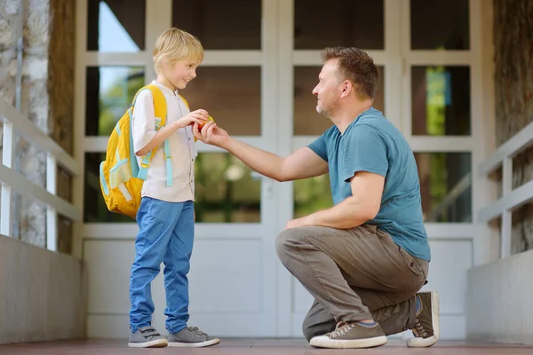 Little schoolboy with his father goes to school after summer holiday. Parent accompanies or meets the child. Quality education for children. Kids back to school concept.