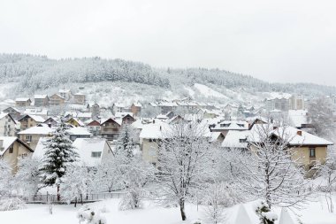 Karlı bir kış gününde, bir yamaçta küçük, sıcak bir Avrupa kasabası. Köy evleri ve ormanlar taze karla kaplı..