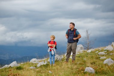 Şirin okul çocuğu ve olgun babası dağda birlikte yürüyüş yapıyor ve doğayı keşfediyorlar. Macera kavramları, çocuklu aileler için keşifler ve yürüyüş turizmi.