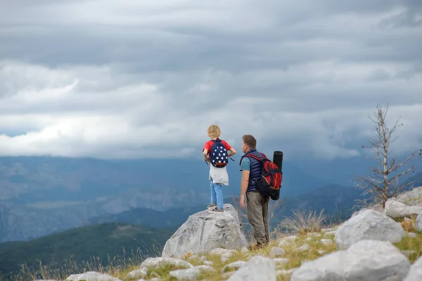 かわいい子供と彼の成熟した父親は山で一緒にハイキングし 自然を探索します 子供は雲を見ている 子供連れの家族のための冒険 スカウティング バックパッキング観光の概念 — ストック写真