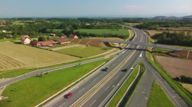 Modern yüksek hız otoyolunun panoramik hava aracı görüntüsü. Yeşil tarlaların arasında resim gibi bir yol. Seyahat, ulaşım ve tarım kavramı