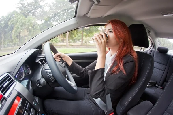 Businesswoman drinking coffee while driving — Stock Photo, Image