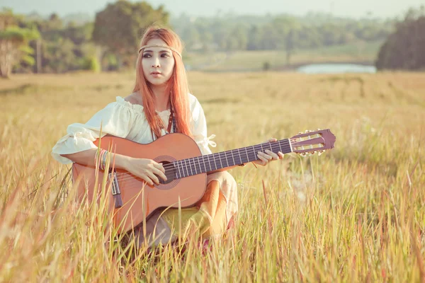 ヒッピーの女の子が芝生の上のギター — ストック写真
