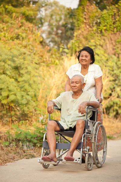 Ανώτερος γυναίκας που ωθεί τα άτομα με ειδικές hasband για αναπηρική καρέκλα — Φωτογραφία Αρχείου