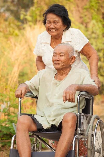 Senior vrouw duwen haar handicap hasband op rolstoel — Stockfoto