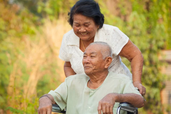Seniorin schubst ihren behinderten Mann im Rollstuhl — Stockfoto