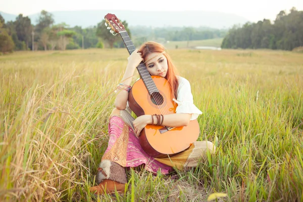 Hippie dívka hrající kytaru na trávě — Stock fotografie