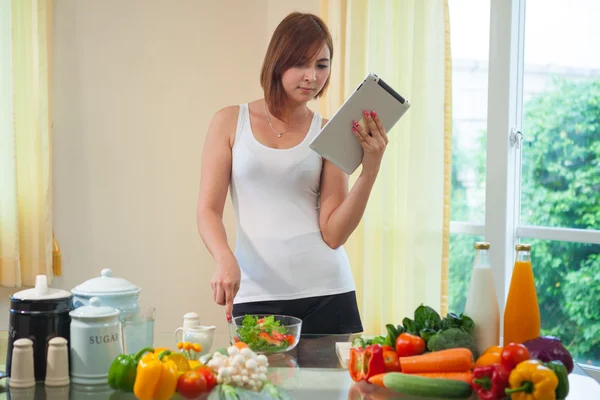 Junge Frau befolgt Rezept auf digitalem Tablet — Stockfoto