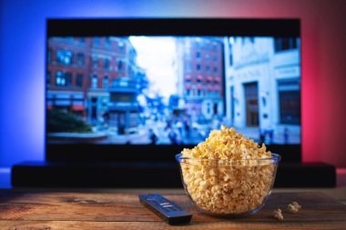 Bir cam kase patlamış mısır ve Uzaktan Kumanda Tv arka planda çalışır. Akşam rahat bir film veya Tv dizisi evde izlerken.