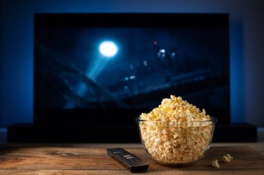 Bir cam kase patlamış mısır ve Uzaktan Kumanda Tv arka planda çalışır. Akşam rahat bir film veya Tv dizisi evde izlerken.