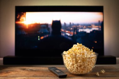 Bir cam kase patlamış mısır ve Uzaktan Kumanda Tv arka planda çalışır. Akşam rahat bir film veya Tv dizisi evde izlerken.
