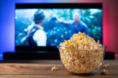 Bir cam kase patlamış mısır ve Uzaktan Kumanda Tv arka planda çalışır. Akşam rahat bir film veya Tv dizisi evde izlerken.