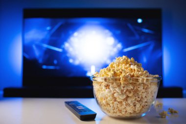 Bir cam kase patlamış mısır ve Uzaktan Kumanda Tv arka planda çalışır. Akşam rahat bir film veya Tv dizisi evde izlerken.
