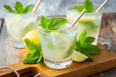 İki bardak limonata ya da naneli mojito kokteyli soğuk, ferahlatıcı içecek ya da buzlu, mavi arka planda buzlu içecek.
