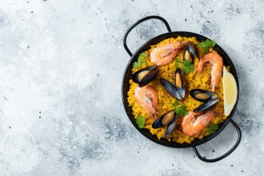 Geleneksel İspanyol deniz ürünleri paella tavada nohut, karides, midye, açık gri beton arka planda mürekkep balığı. Kopyalama alanı olan üst görünüm