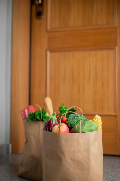 Food shopping bags stand at the door of the house or apartment. Vegetables and fruits delivery during quarantine and self-isolation