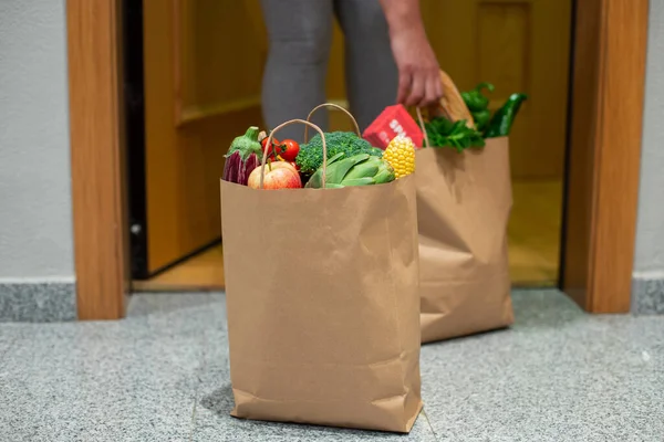 Una donna prende un sacchetto di cibo alla porta di casa sua. Coronavirus. Quarantena. Resta a casa, Shopping online. Consegna di ortaggi e frutta durante la quarantena e l'autoisolamento — Foto Stock