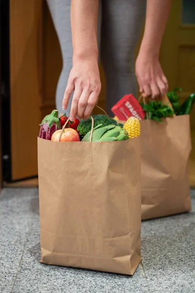 Una donna prende un sacchetto di cibo alla porta di casa sua. Coronavirus. Quarantena. Resta a casa, Shopping online. Consegna di ortaggi e frutta durante la quarantena e l'autoisolamento — Foto Stock