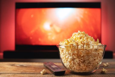 Bir cam kase patlamış mısır ve Uzaktan Kumanda Tv arka planda çalışır. Akşam rahat bir film veya Tv dizisi evde izlerken.