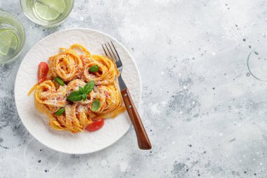 Lezzetli iştah açıcı klasik İtalyan tagliatelle makarnası domates soslu, peynirli parmesan peyniri ve tabakta fesleğen. Yukarıdan bak, yatay. Kopyalama alanı olan üst görünüm.