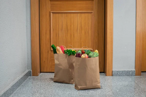 Food shopping bags stand at the door of the house or apartment. Vegetables and fruits delivery during quarantine and self-isolation